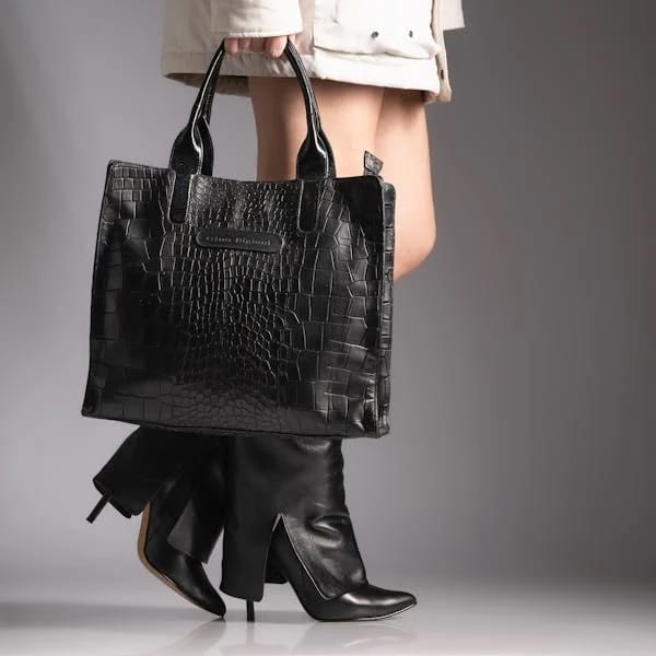 Visuel femme élégante marchant avec un sac a main en cuir noir et des bottes en cuir noir